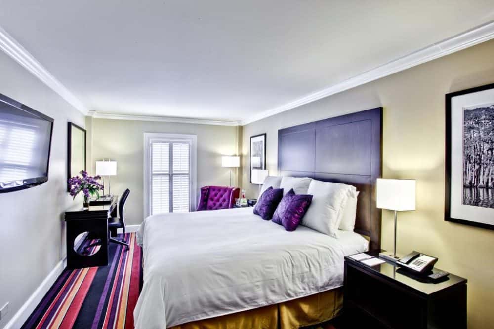 A bedroom with a bed and desk in a room Hotel Le Marais in New Orleans