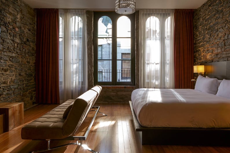 A bedroom with a large window at Le Petit Hotel in Montreal