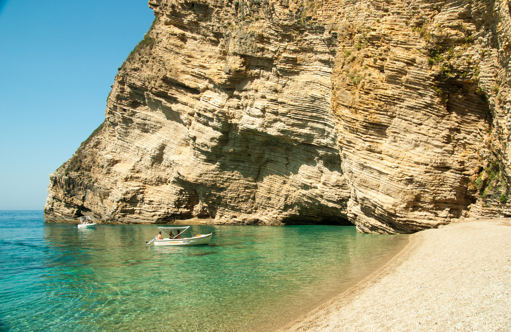 A person sitting on a rock next to a body of water at Liapades resort in Corfu