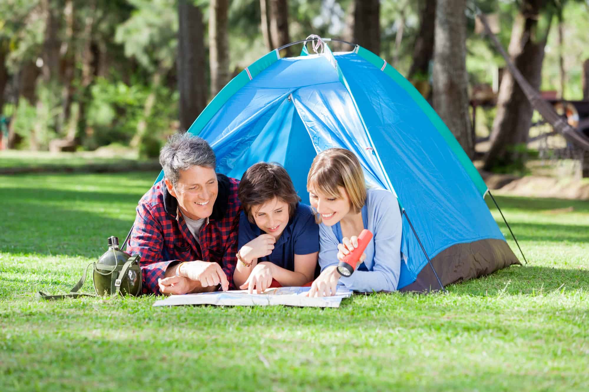 A family on a staycation reads a map while in a tent at a campsite.